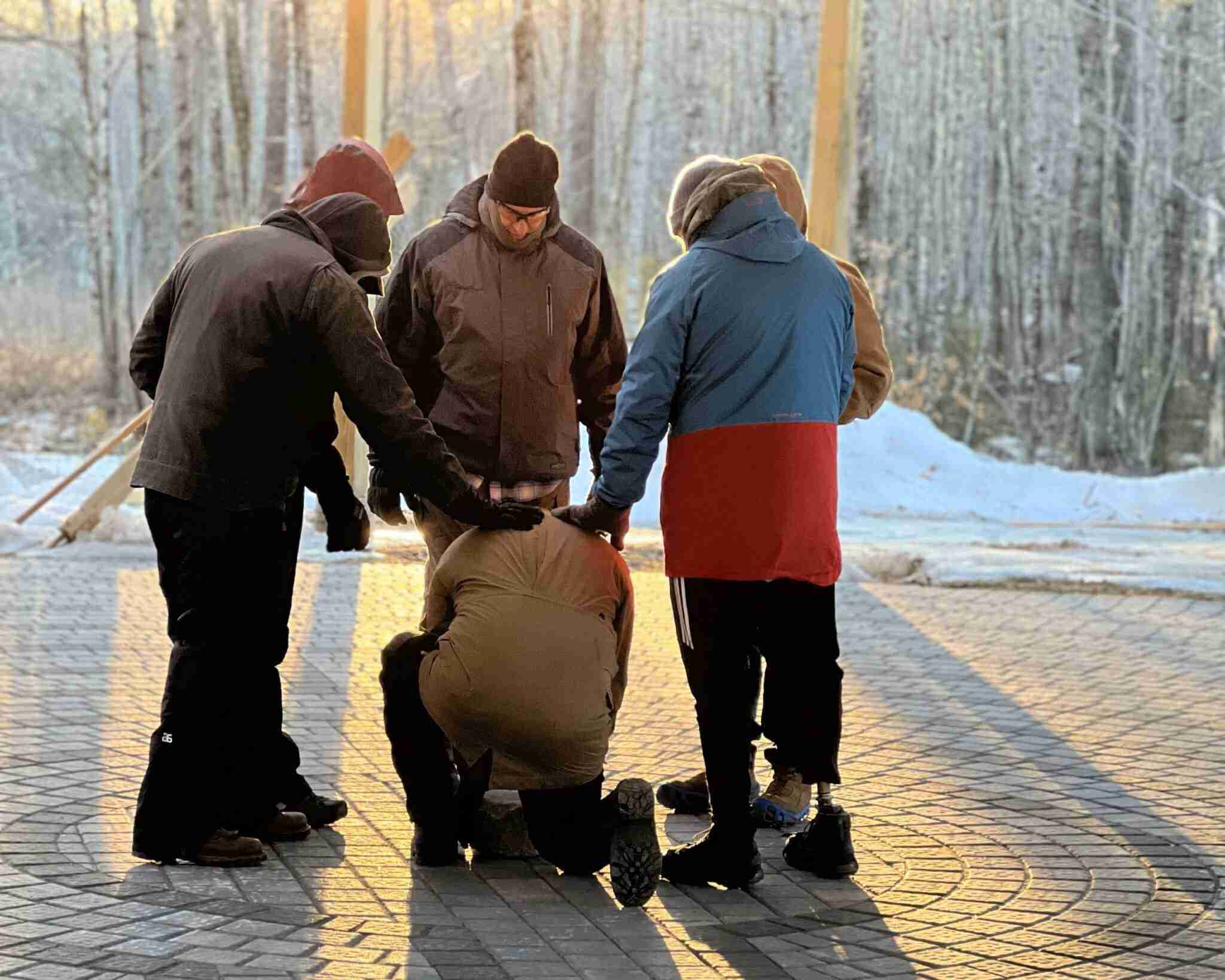 group of men standing supporting each other
