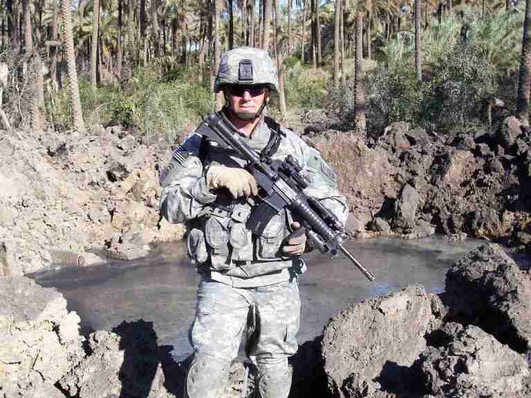 man in military gear holding a gun in the field